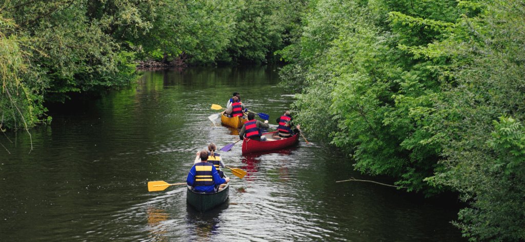 Stay safe on the water. People canoeing down a river in summer.