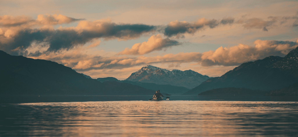 Paddlers on lake at sunset showing how to take a great paddling photo. Join British Canoeing