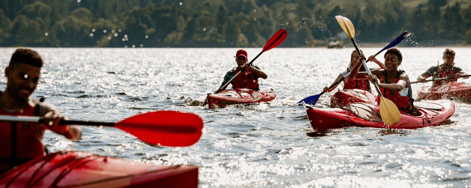 a group of kayakers paddling towards the camera with smile son their faces enjoying the water