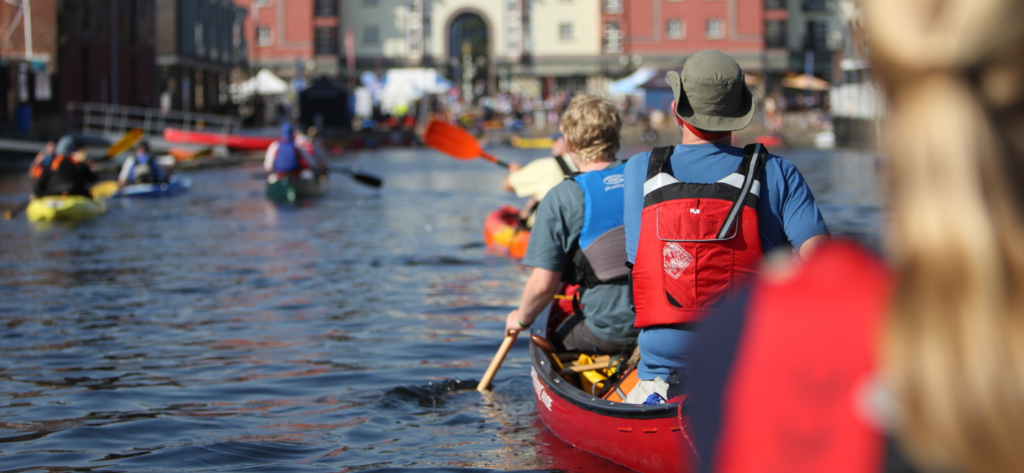 group of people mixed ages paddling together in the sun