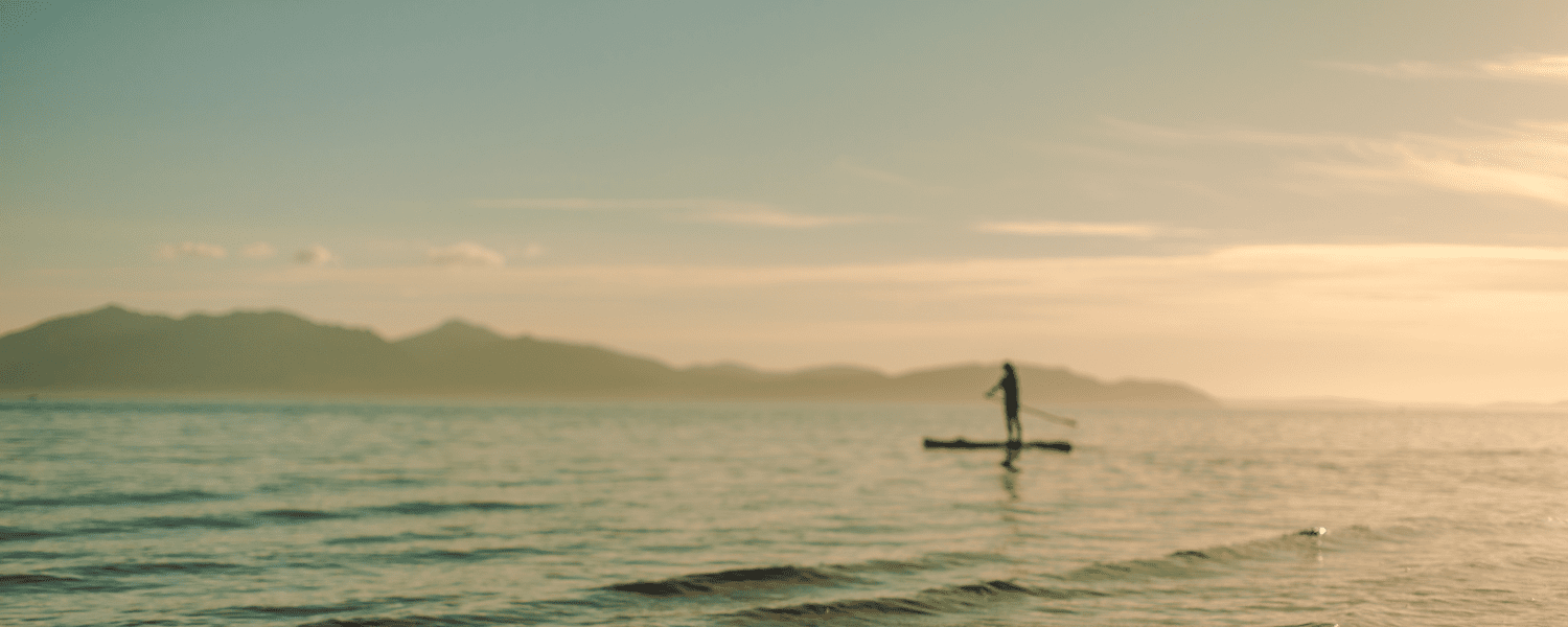 individual paddle boarder at sunset