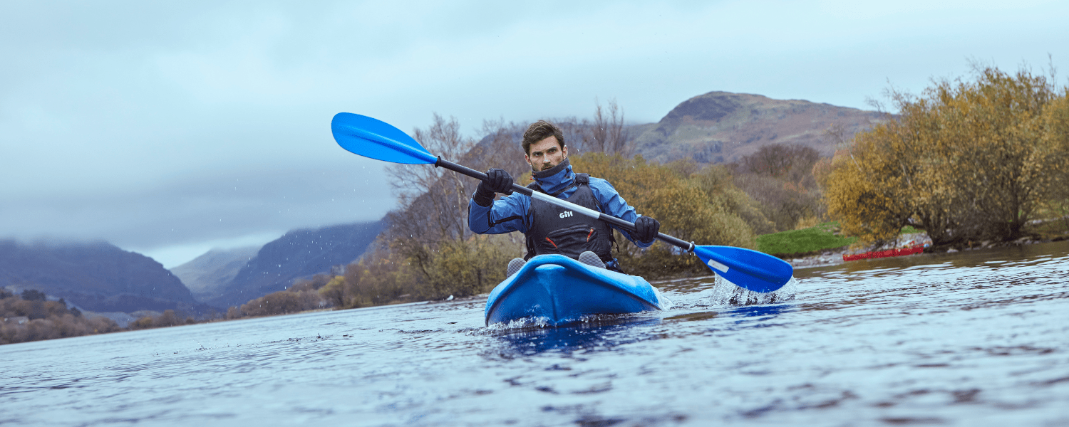 solo kayaker on the water against an autumnal backdrop