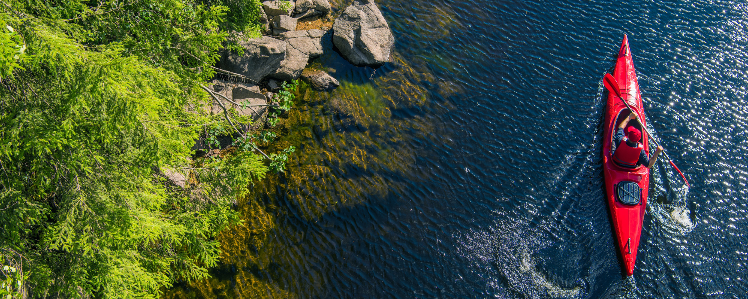 kayaker paddling along a bank down a river