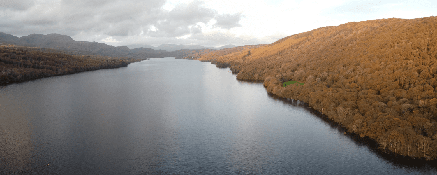 an aerial photo of coniston water with orange leaves on the trees next to the lake