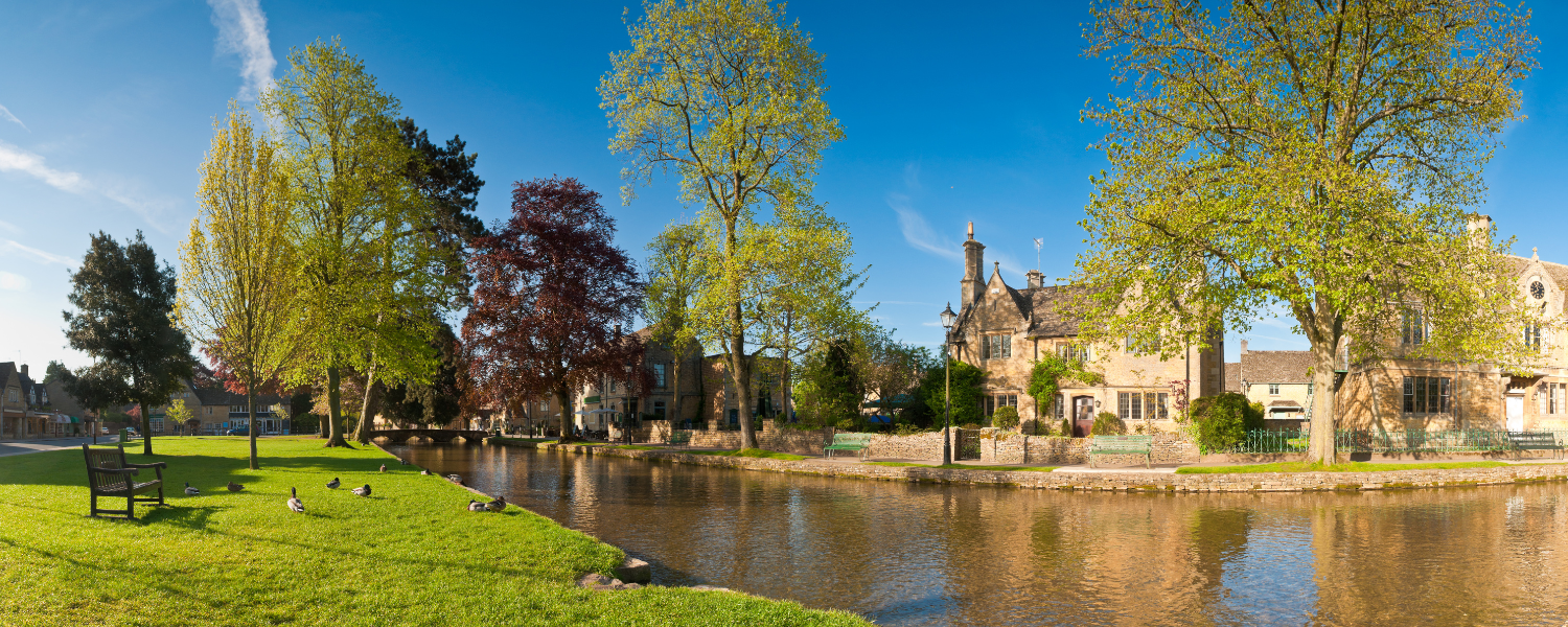 a canal in the cotswolds with an old stone building on the far side