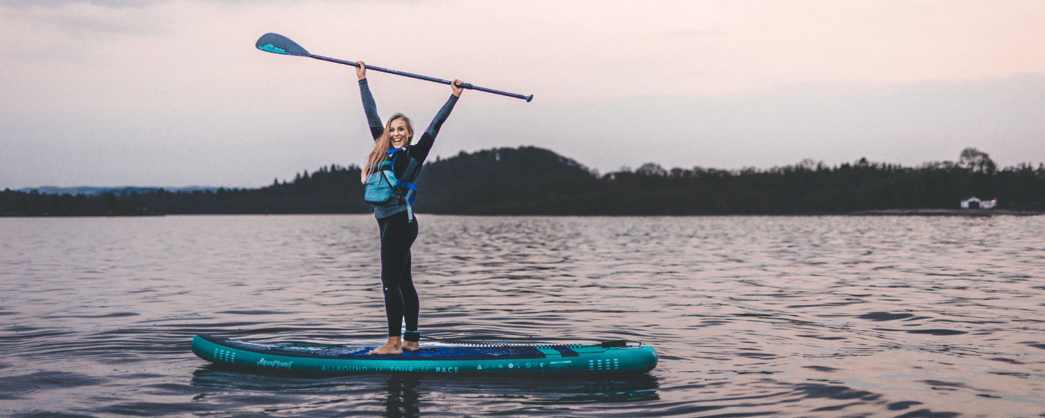 woman on a paddle board stretching while on the water