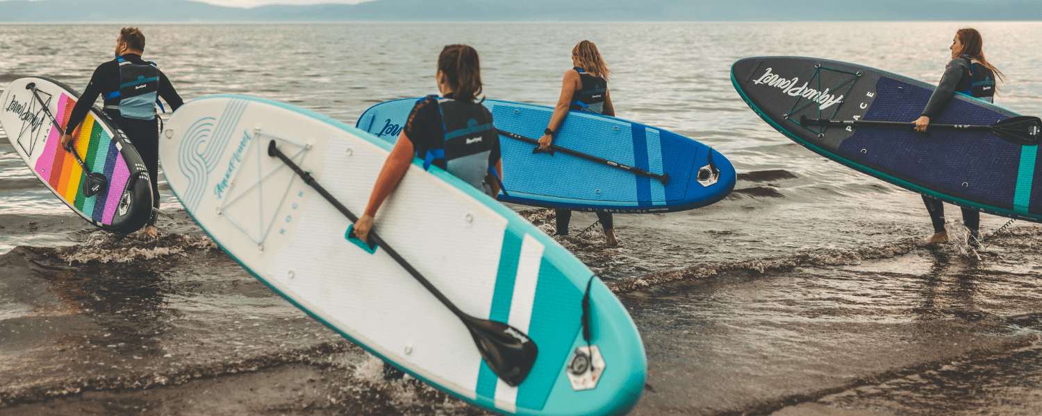 group of paddle boarders holding their boards as they enter the water