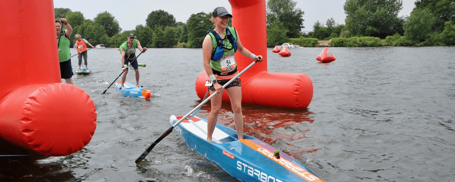 paddle boarders coming under the finish archway during a race