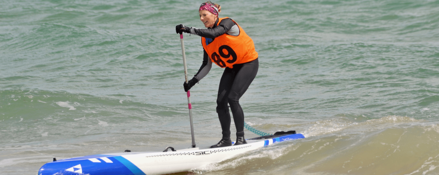 an older woman coming ashore during a sup race