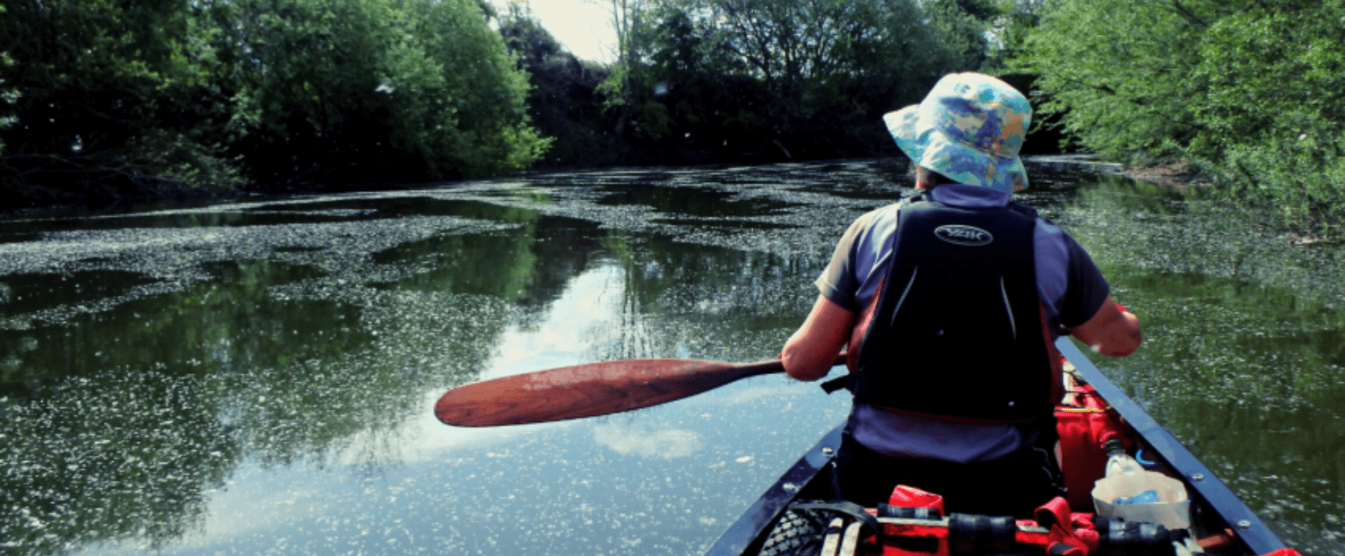 Linda in the front of the canoe paddling down a calm river