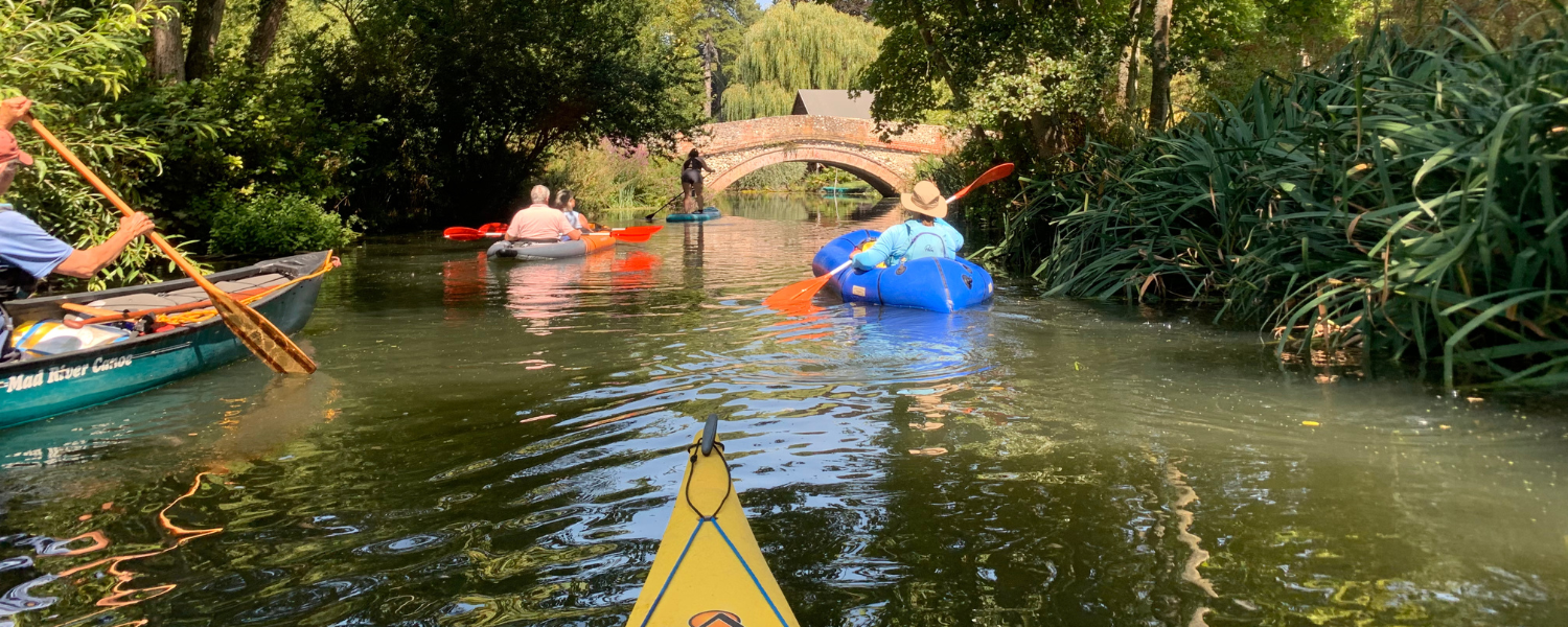 a collection of different crafts paddling down a calm river