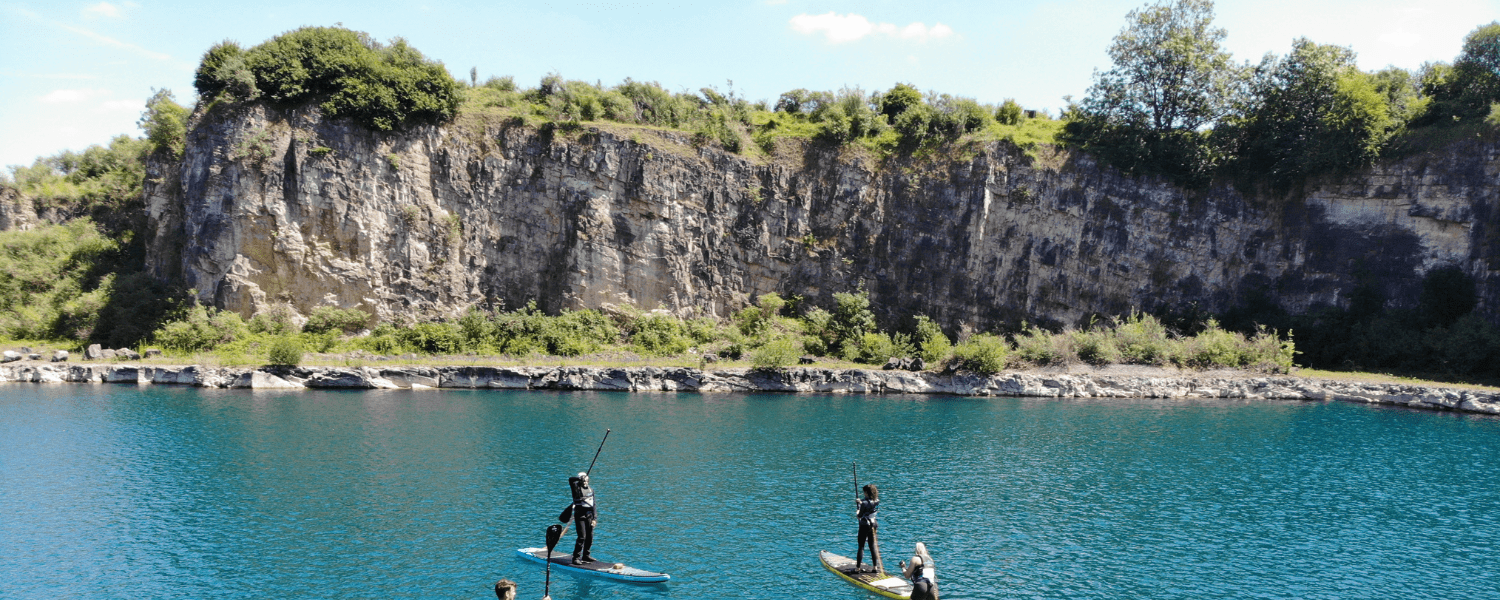 group of paddle boarders paddling up to a cliff face