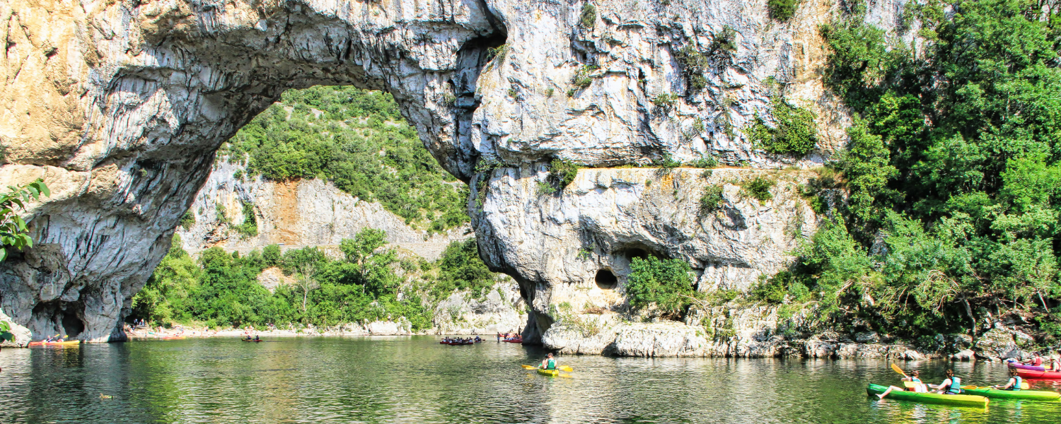 a group of kayakers paddling next to a giant arch in a cliff