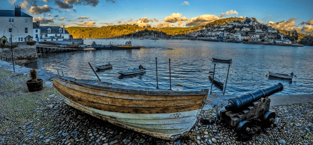 old row boats pulled up on a pebble beach in a old town harbour