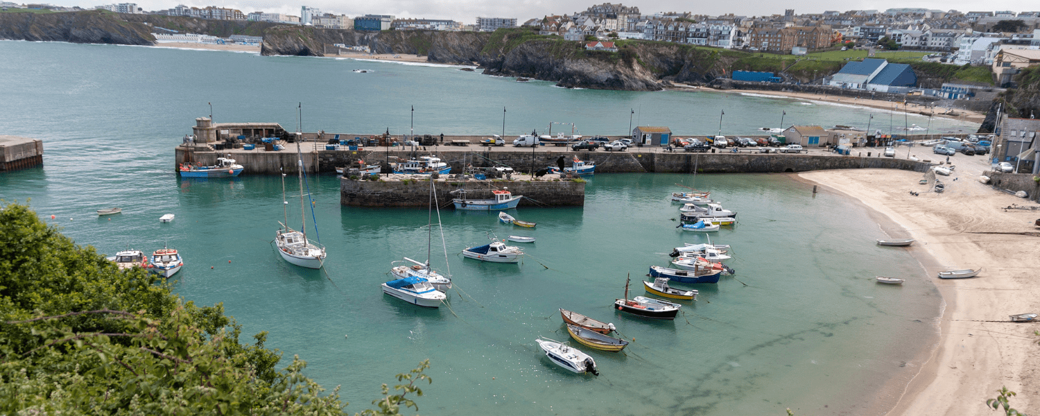 newquay harbour with a sandy beach and calm blue seas