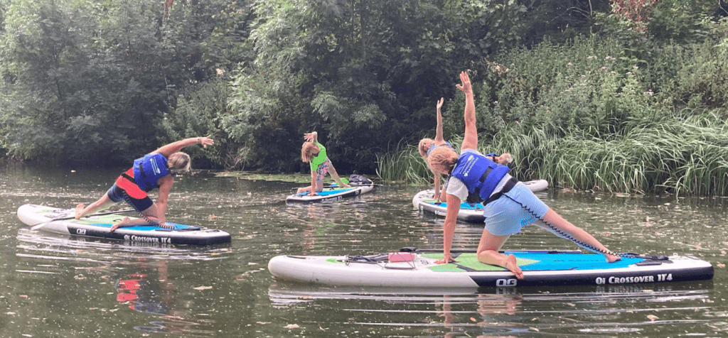 a group of people being led through yoga on paddle boards