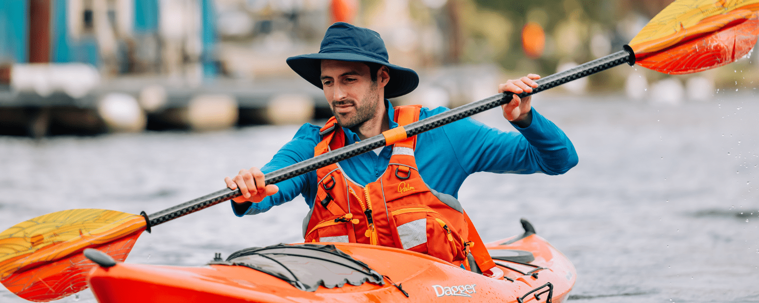 a man kayaking with long sleeve and sun hat to protect him from the sun