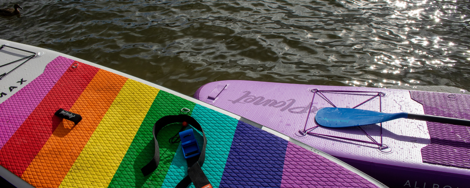 a pair of inflatable paddle boards next to the water in the sun