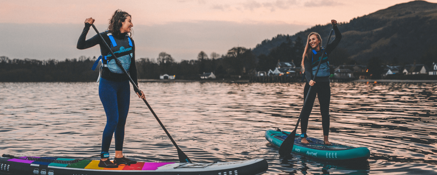 two women talking while on paddle boards on water