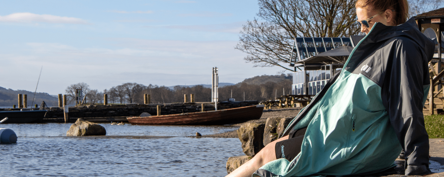 Someone in an aqua parka by the water after paddling