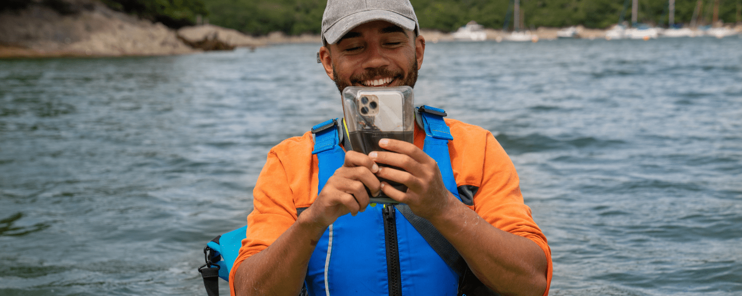 man using his phone in an aquapac while on a kayak