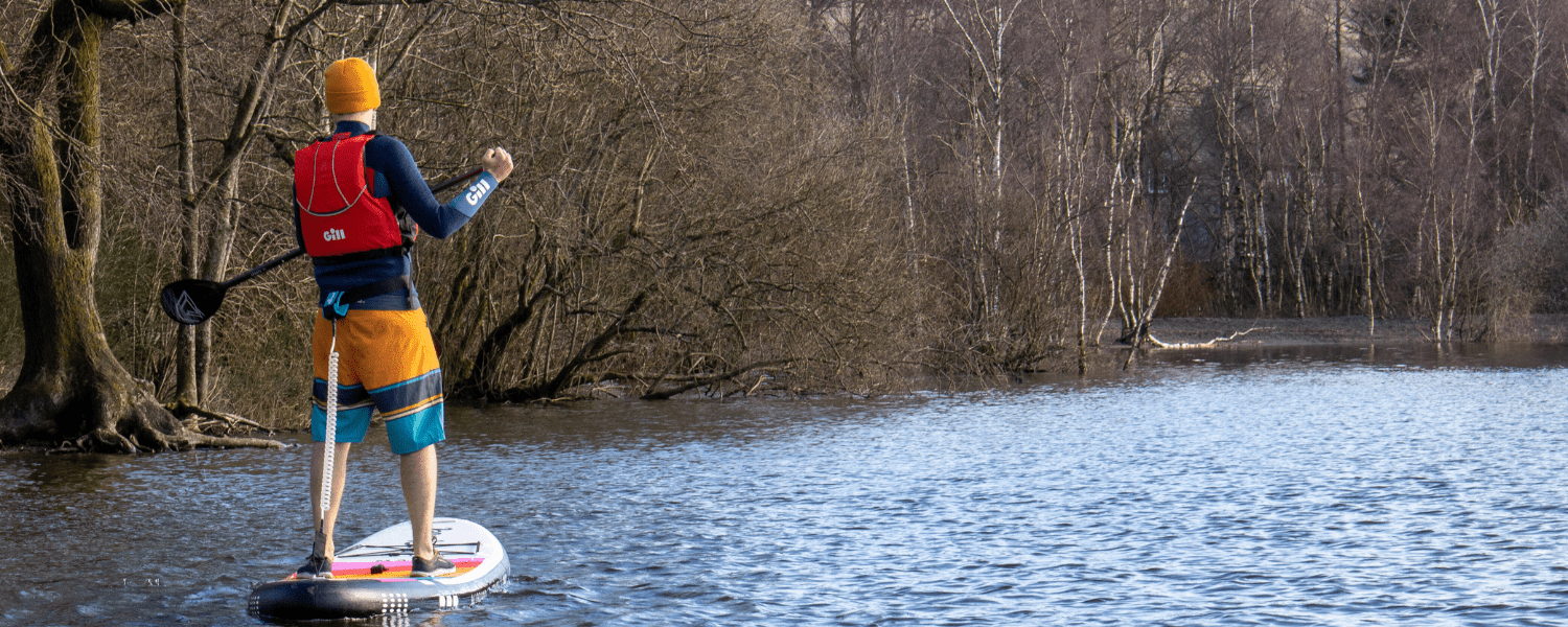 a man on a SUP with a gill beanie on