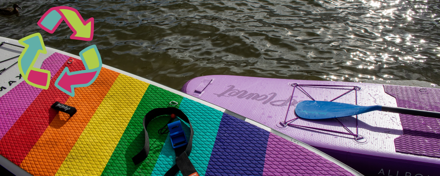 two paddle boards next to the water with a recycle logo on them