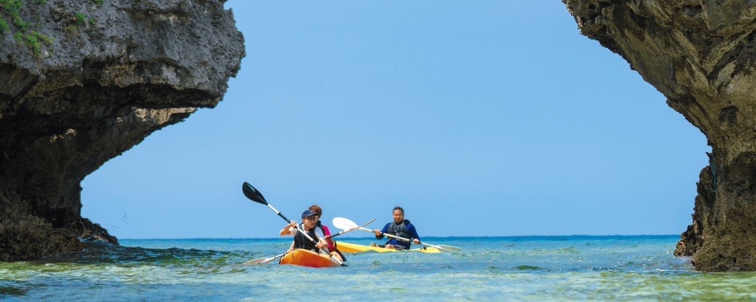 a group of kayakers paddling between rocks on the sea