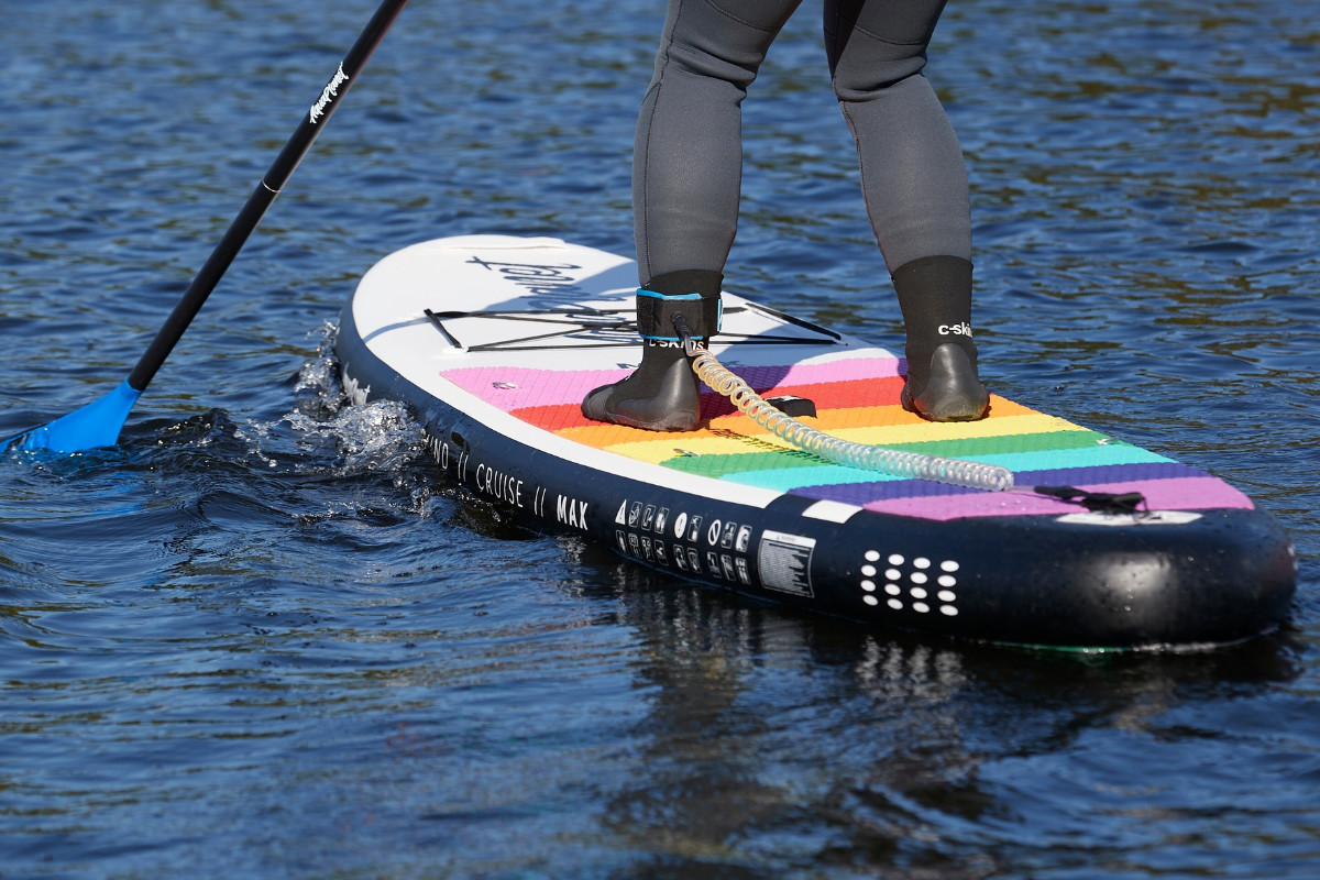 Female paddleboarder wearing neoprene boots and leggings for their autumn paddle.