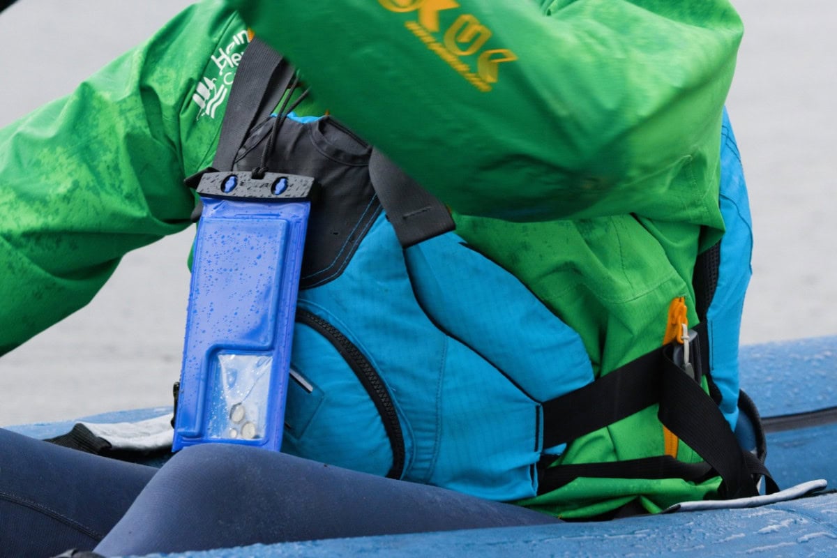 Kayaker in the Lake District with mobile phone in a waterproof case. Wearing the correct kit for paddling in autumn.
