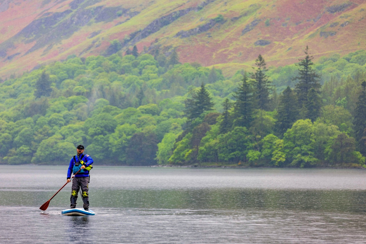 Male paddleboarder in the Lake District in autumn