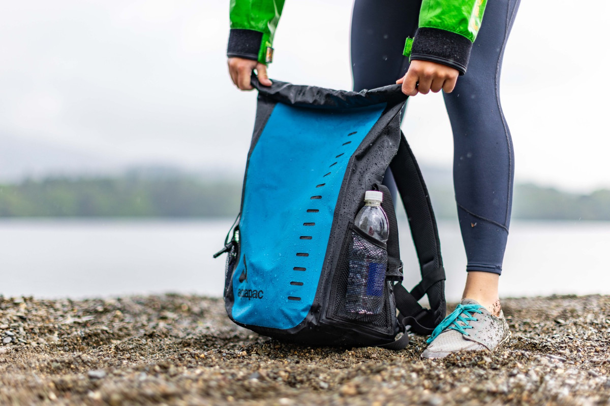 Female paddler getting ready to get out on the water. Packing her dry bag with kit, food and a drink.